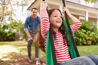 Father Pushing Daughter On Garden Swing At Home