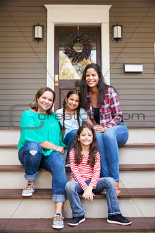 Female Multi Generation Family Sit On Steps in Front Of House
