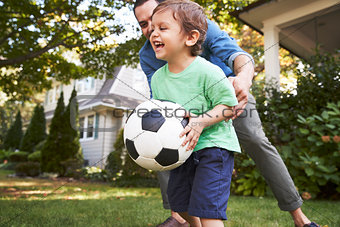Father Playing Soccer In Garden With Son