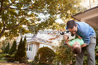 Father Playing With Soccer Ball In Garden With Son