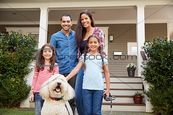 Portrait Of Family Standing in Front Of House With Pet Dog