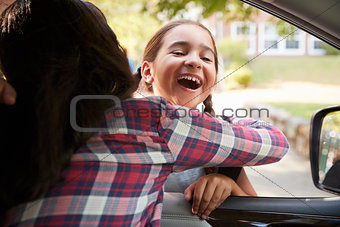 Mother In Car Collecting Daughter In Front Of School Gates