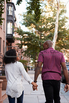 Rear View Of Couple Walking Along Urban Street In New York City
