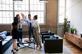 Businessmen and women high five at motivational meeting