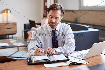 Businessman at desk writing notes