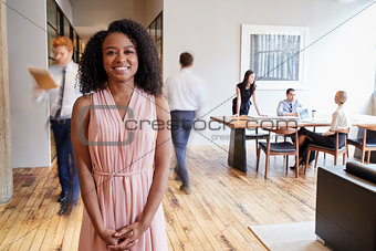 Portrait of young black woman in a busy modern workplace