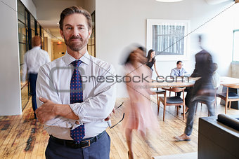Portrait of middle aged white man in a busy modern workplace