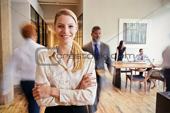 Portrait of young blonde woman in a busy modern workplace