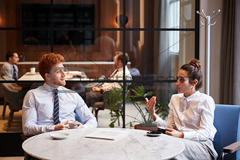 Male and female colleagues talk over coffee at office cafe