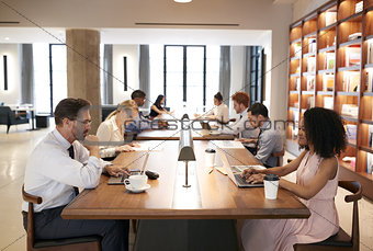 Colleagues at desks in a busy open plan office, close up