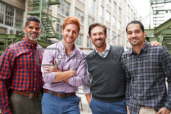 Four male coworkers smiling to camera outside