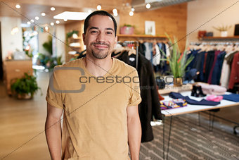 Smiling young Hispanic man standing in a clothes shop