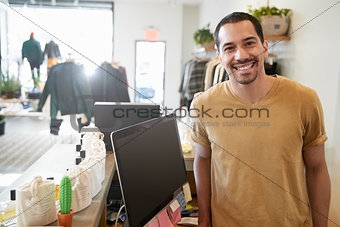 Male assistant smiling behind the counter in a clothes store