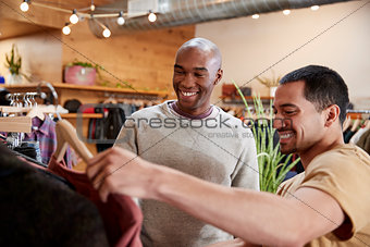 Two male friends look at clothes in a clothes shop, close up
