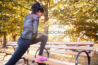 Young black woman stretching on a bench in a Brooklyn park