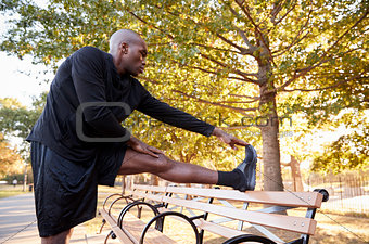 Young black man stretching leg in a Brooklyn park