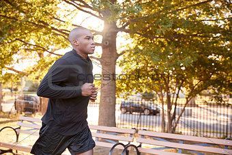 Young black man jogging in a Brooklyn park, close up