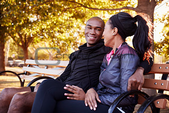 Young black couple sitting on bench in Brooklyn park