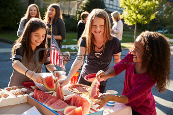 Girls helping themselves to watermelon at a block party
