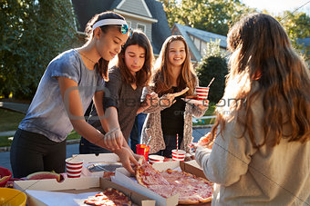 Teen girls sharing a pizza at a neighbourhood block party