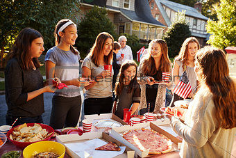 Group of teen girls talking over food table at a block party