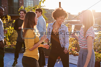 Female friends dancing and drinking at a rooftop party