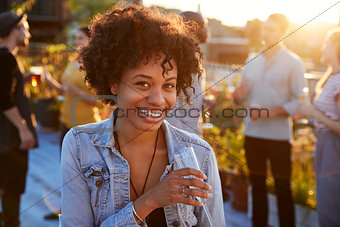 Young black woman at a rooftop party smiling to camera