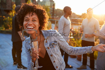 Young woman dancing at a rooftop party smiling to camera