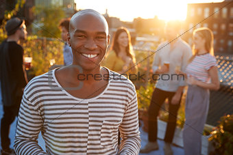 Young black man at a rooftop party smiling to camera