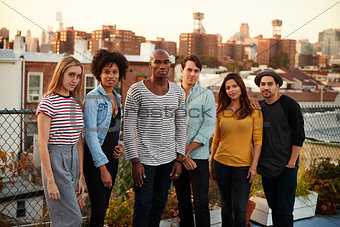 Six adult friends standing together on a Brooklyn rooftop