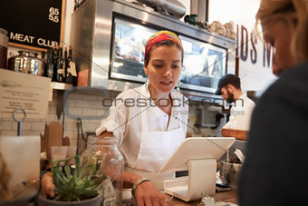 Young woman serving a customer in a butcher's shop