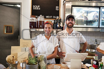 Man and woman ready to serve behind the counter at butcher's