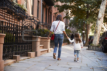 Mother and daughter walking down the street, back view