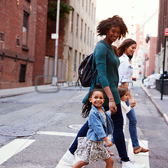 Two mother friends with daughters crossing road, close up