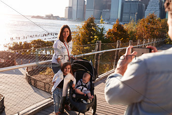 Young family with two daughters taking a photo on footbridge