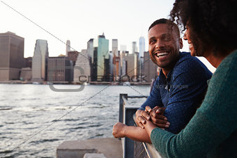 Young black couple standing on quayside, side view