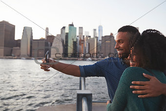 Young black couple taking photo on quayside, side view