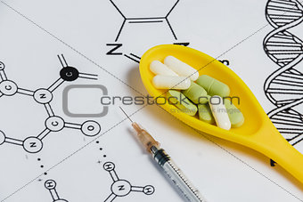 Assortment of Pills, Tablets and Capsules in Yellow Spoon, Syringe on White Background with Chemical Formula.