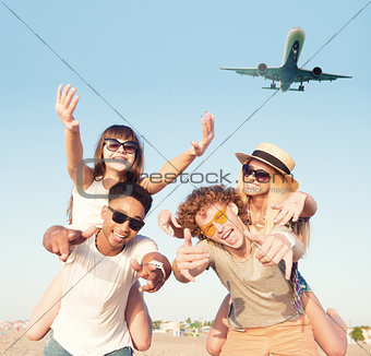 Happy smiling couples playing at the beach with aircraft in the sky