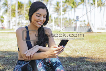 Pretty sportswoman using phone in park
