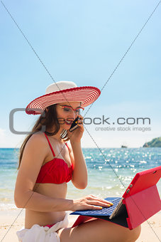 Fashionable young woman talking on mobile phone at the beach