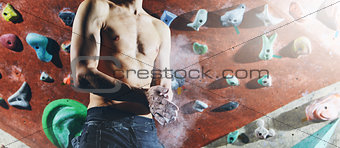 man climber preparing to climb indoors on climbing gim