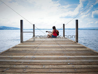 Woman playing guitar by the lake