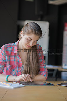 Portrait of a Smiling Woman Working on Tablet lndoors.