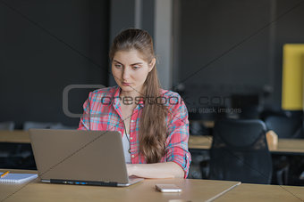 Portrait of a Serious Woman Working on Laptop lndoors.