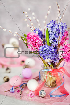 Easter eggs with beautiful hyacinths and willow bouquet on light