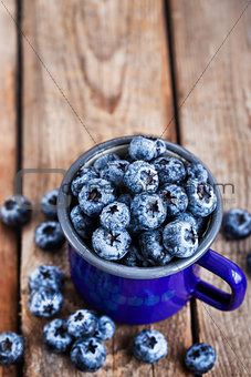 Fresh ripe blueberries and in blue enamel mug