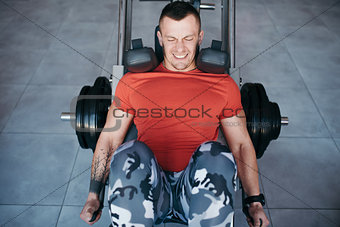 Fit man training legs on leg press machine in the gym