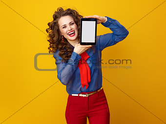 woman against yellow background showing tablet PC blank screen