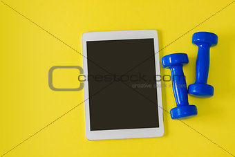 Sport flat lay composition tablet and blue dumbbells